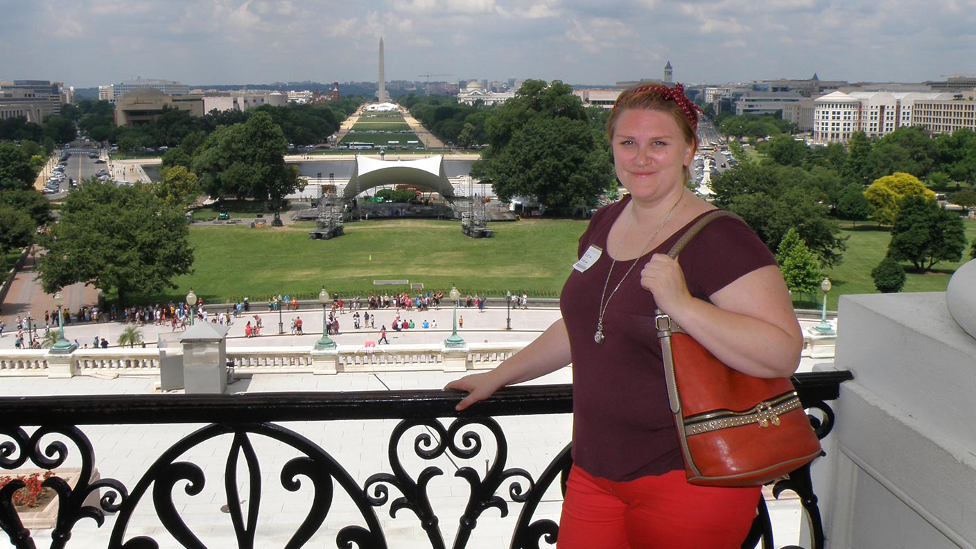 Liljan framför ett räcke med utsikt över Washingtonmonumentet.