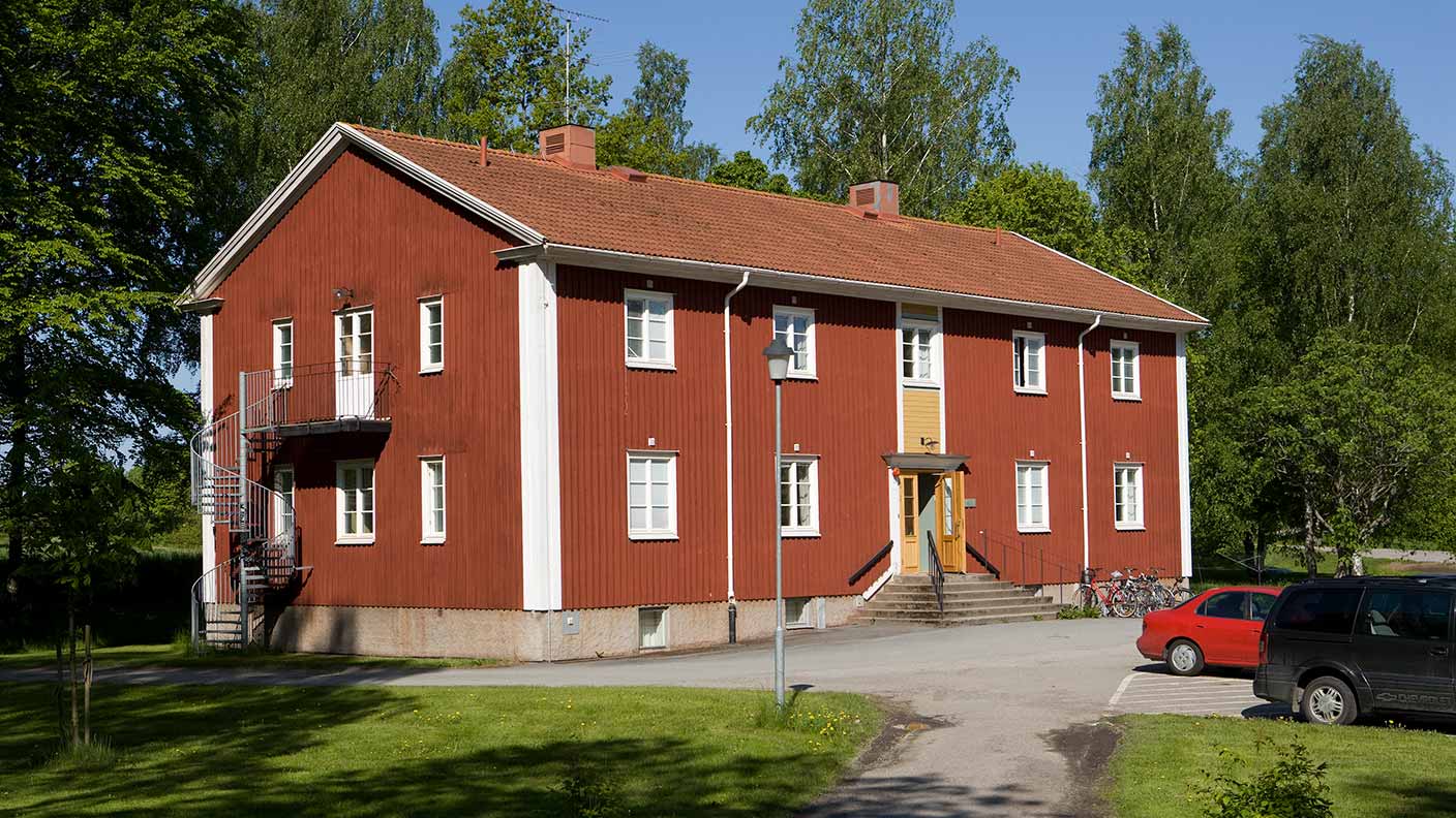 Ett rött hus med vita knutar byggt in länga med två våningar.