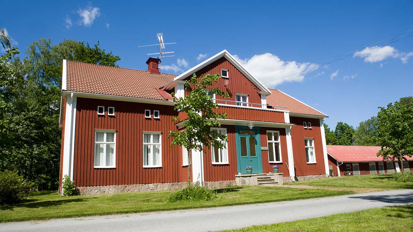 Hantverkshuset i sommarskrud. Huset är ett rött trähus i två våningar med vita knutar. 