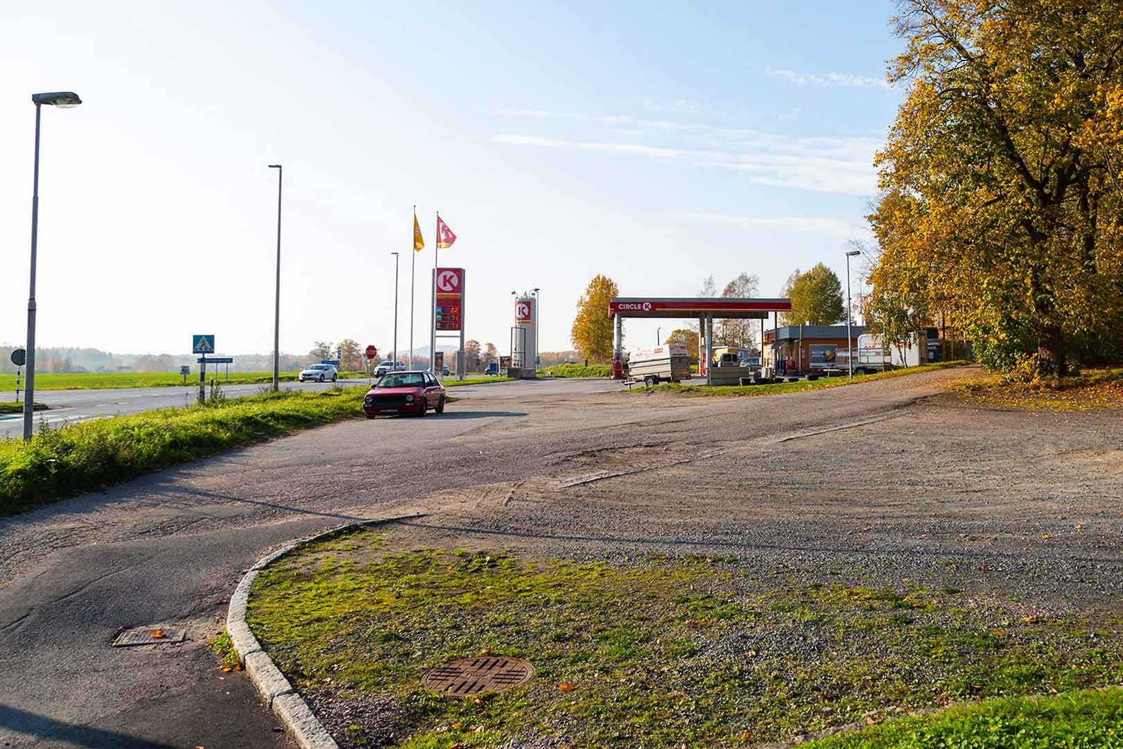 En grusplan och en gångväg i förgrunden. I bakgrunden en bensinmack - Circle K.