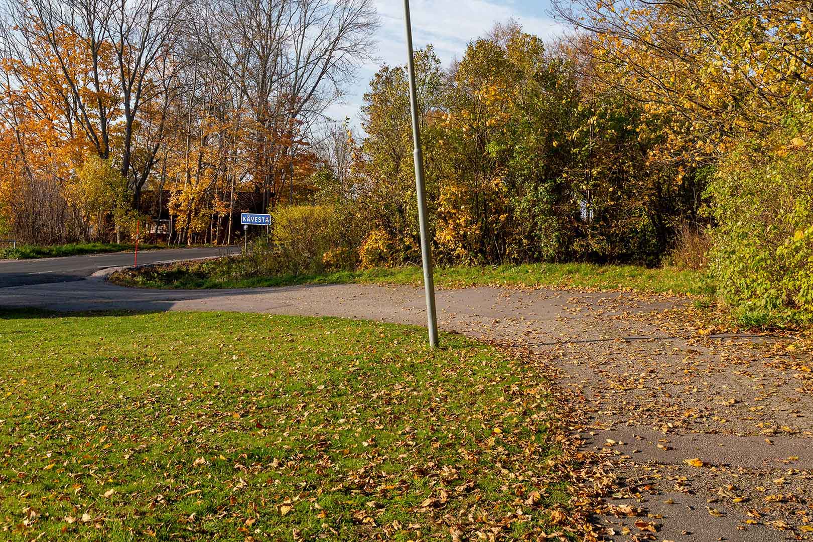 Gångvägen kröker sig åt vänster, i bakgrunden ser du en bilväg.