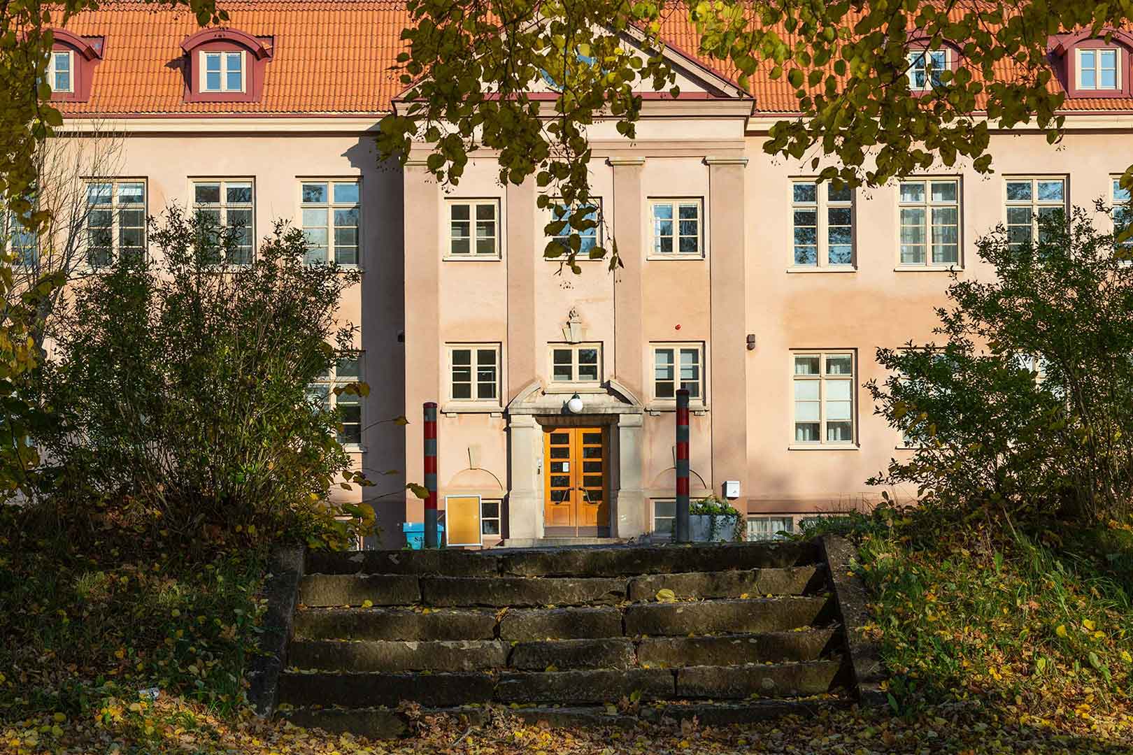 Stora skolhuset skymtas bakom ett par buskar.