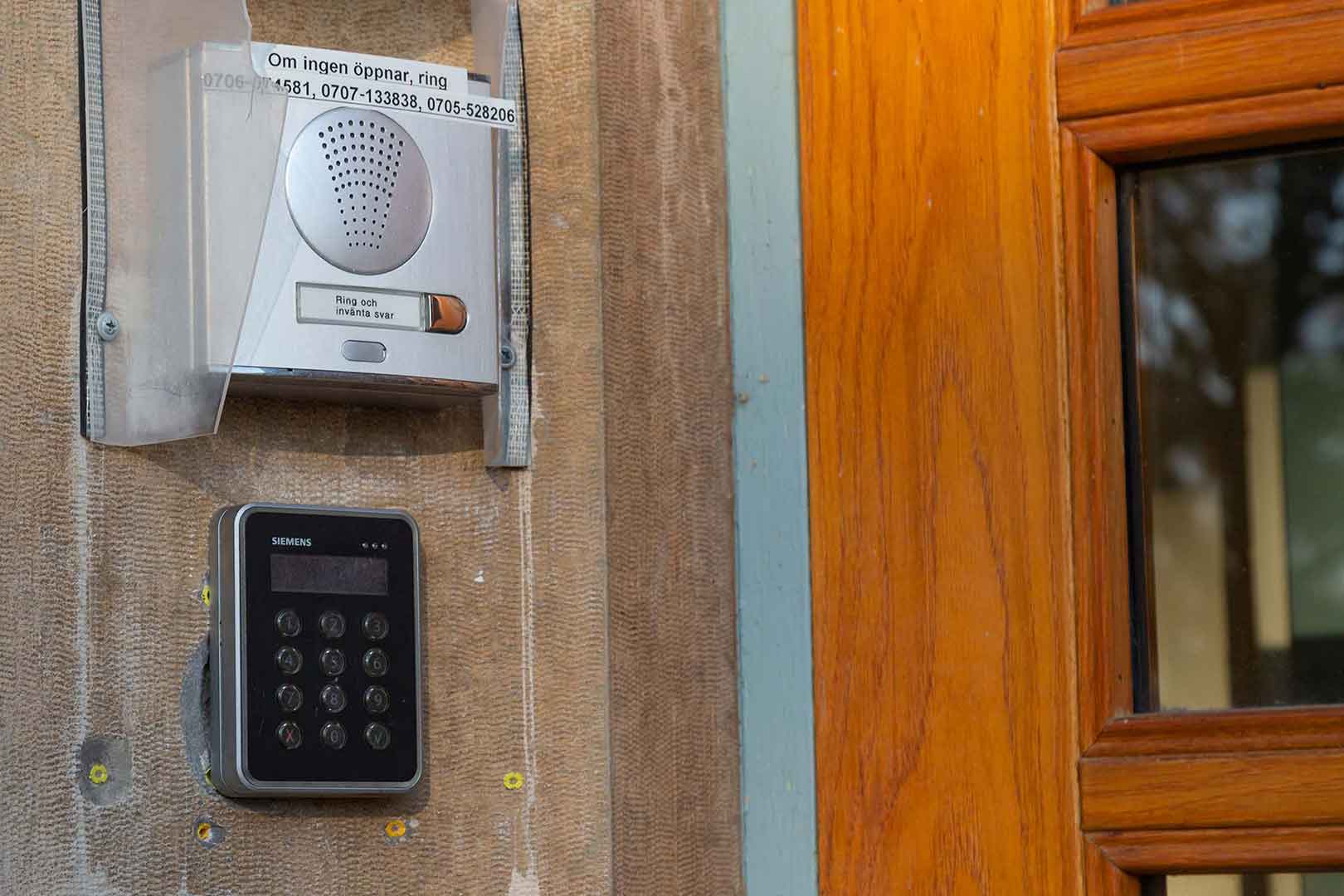 En porttelefon i silver som sitter bredvid dörren.